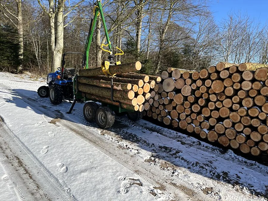 Stablet tømmer og kranvogn ved skovvejen i sne